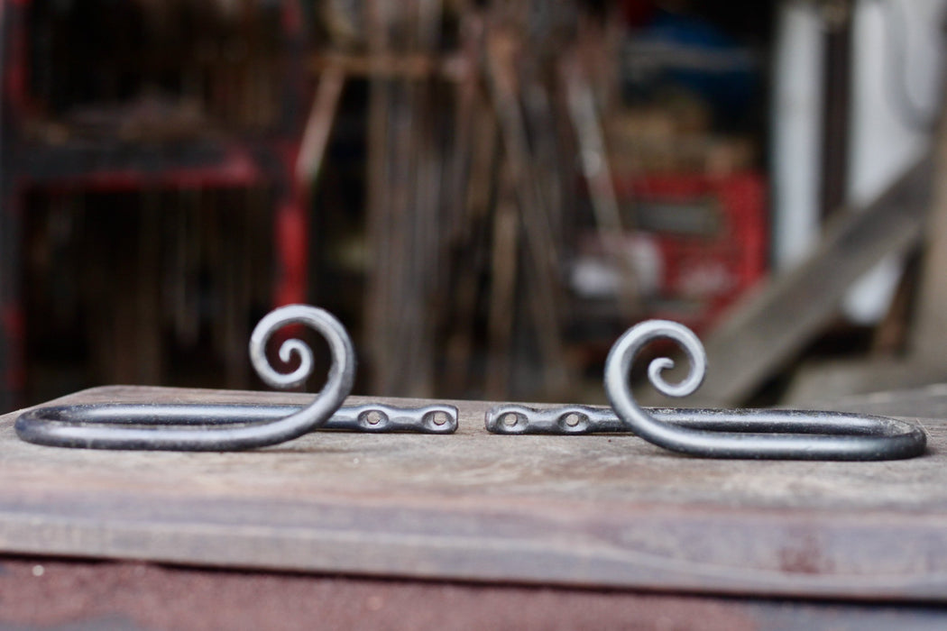 a set of blacksmith hand forged curtain holdback with a curl design by Wicks Forge