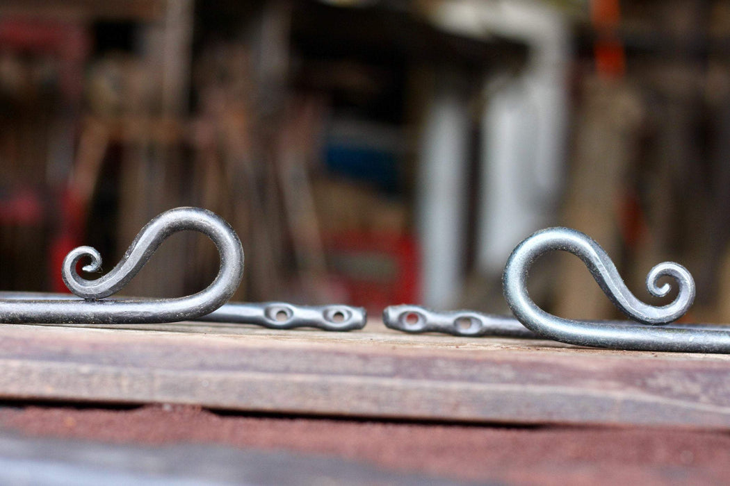 a set of blacksmith hand forged curtain holdback with a reverse curl design by Wicks Forge