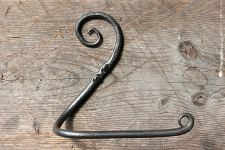 a blacksmith hand forged toilet paper holder with a curl detail by Wicks Forge