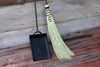 hand woven fire broom and wrought iron shovel set by wicks forge against a wooden wall 