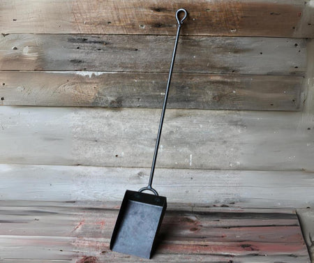 Black metal dustpan against a rustic wooden background