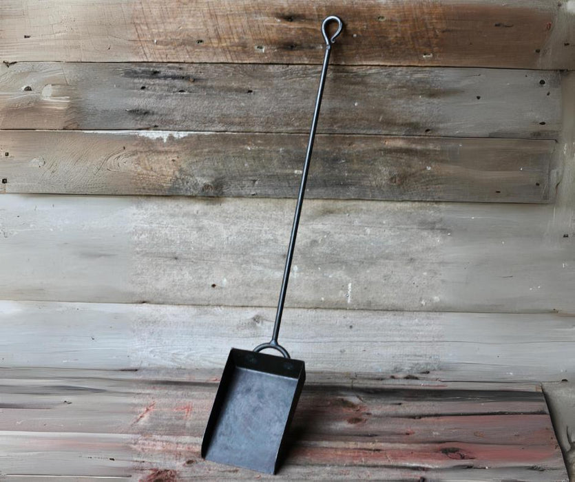 Black metal dustpan against a rustic wooden background