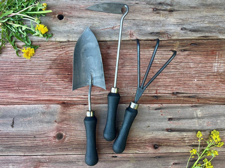 garden tools wrought iron with yellow weeds showing on a wooden surface by wicks forge 