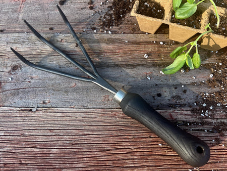 Gardening tool on a wooden surface with plants in the background
