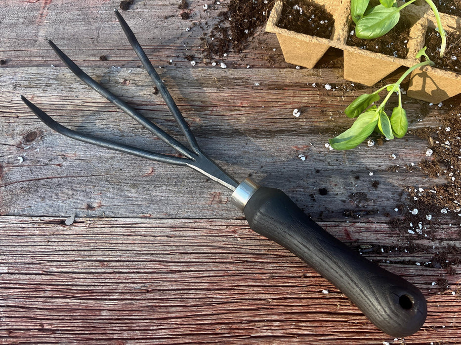 Gardening tool on a wooden surface with plants in the background