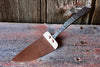 cake slicer made of brass and iron on a wooden surface by wicks forge 
