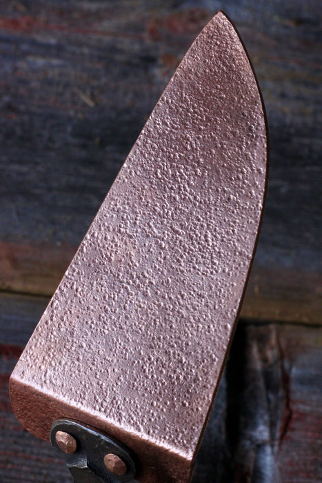 a brass cake slicer with rustic wooden background by wicks forge 