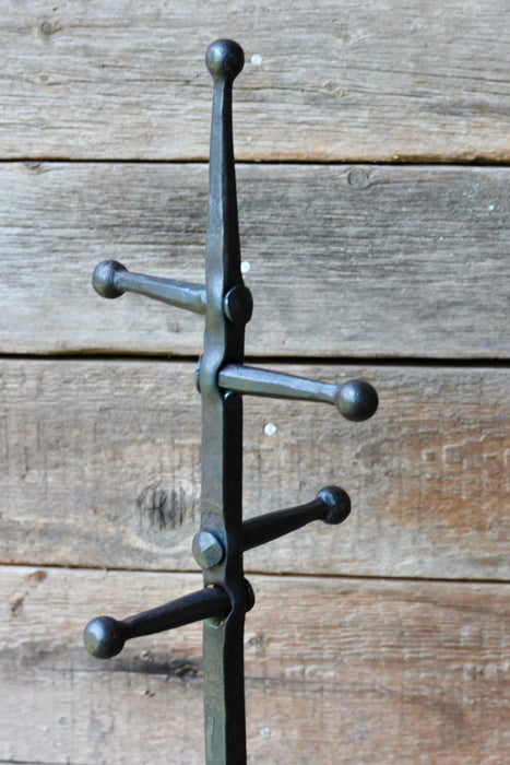 fire tools stand against a wooden panel wall 
