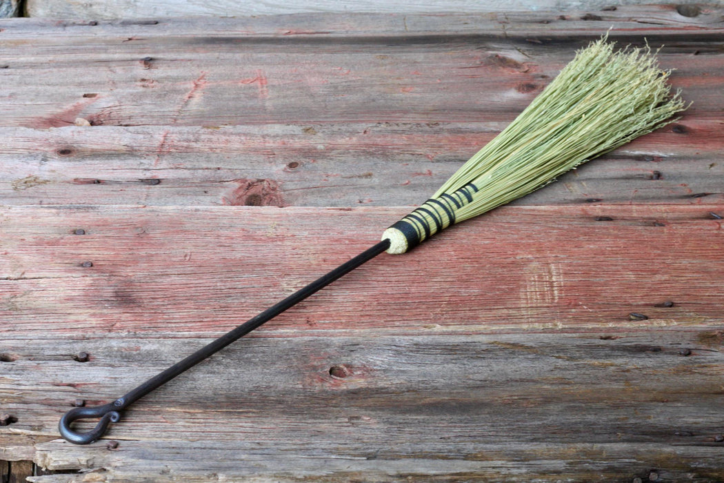a fireplace broom on a rustic wooden surface by wicks forge 