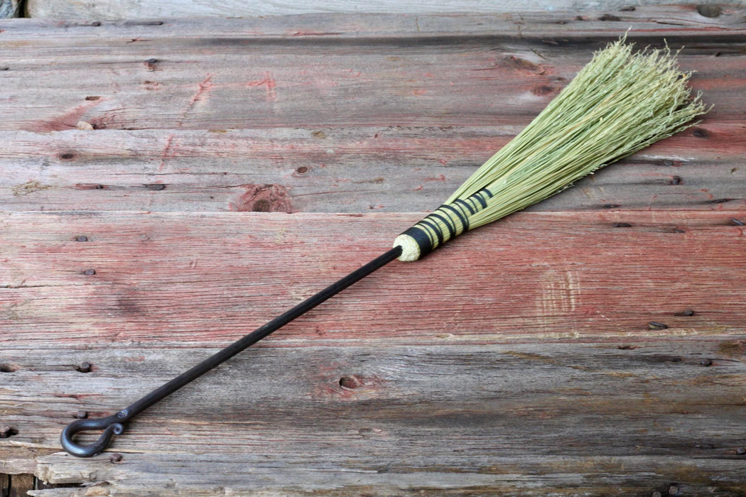 fireplace bristle broom with hand forged iron handle on a wooden surface by wicks forge 