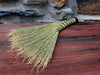 a yellow broom on a wooden table and rustic stone wall in the background by wicks forge 