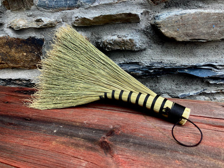 Broom with black and yellow handle on a wooden surface and stone wall background