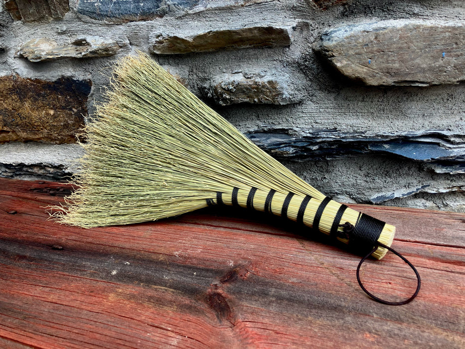 Broom with black and yellow handle on a wooden surface and stone wall background