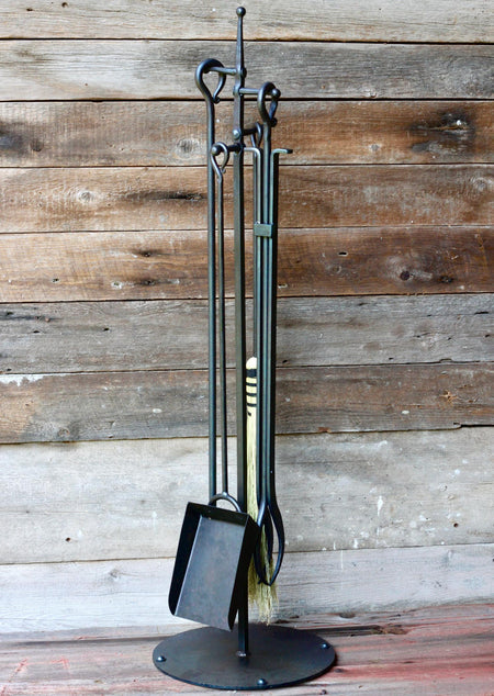 fireplace tools on a stand against a wooden background by wicks forge 
