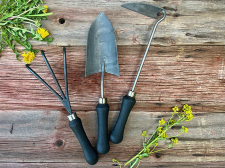 Gardening tools and dandelions on a wooden surface by wicks forge 