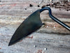 black garden weeder made of iron against a wooden background 