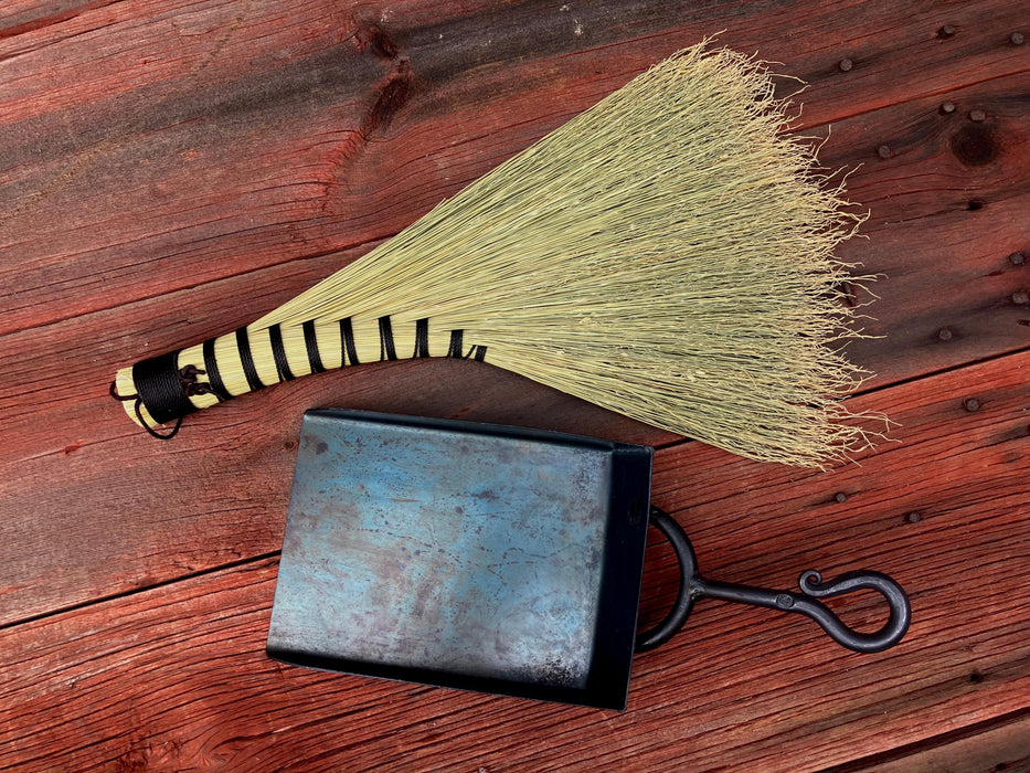 a broom and shovel against a dark wood background by wicks forge 