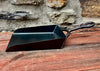 a black hand shovel on a wooden table and stone wall in the background 