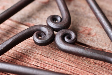 close up of scrolls of trivet on a wood surface 