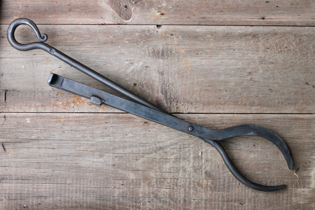 Black metal tongs on a wooden surface