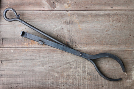 Black metal tongs on a wooden surface