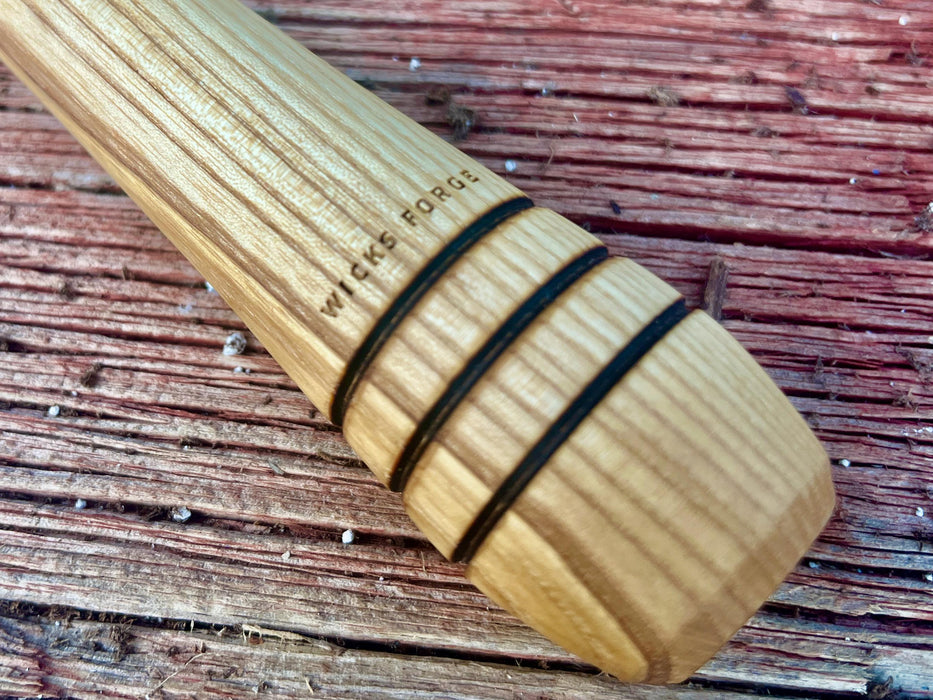 natural wood handle of the wicks forge garden fork against a dark wood surface 