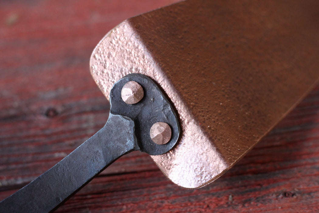 cake slicer showing rivets on a wooden background by wicks forge 