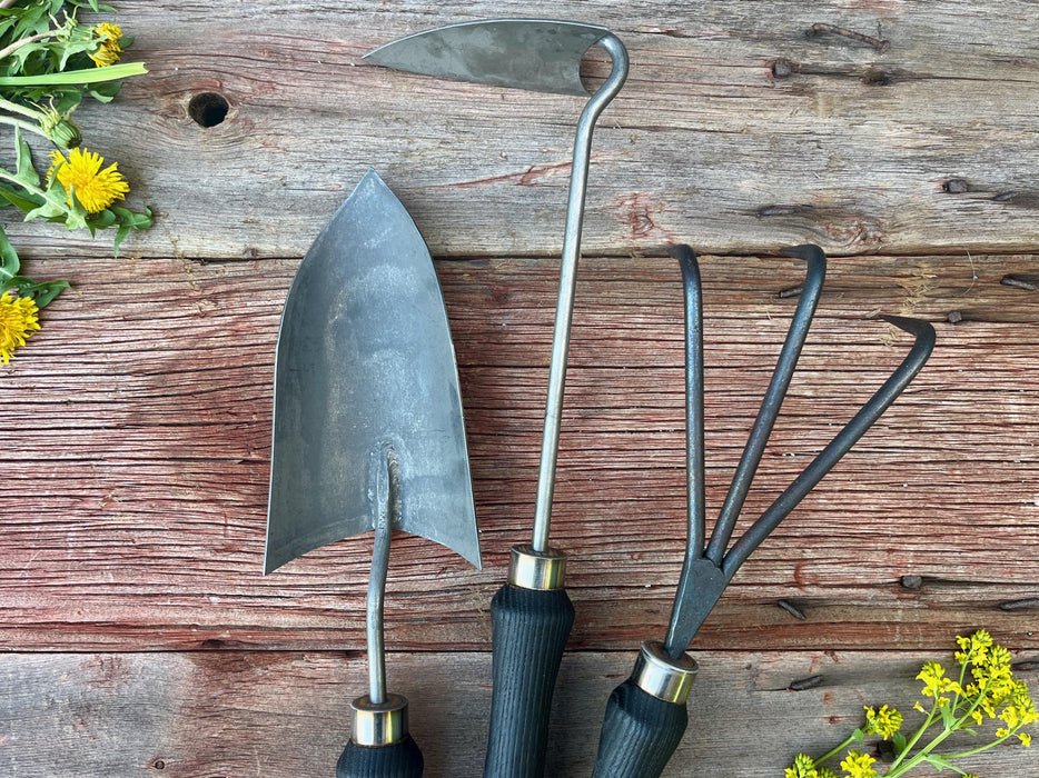 Gardening tools on a wooden surface with dandelions and yellow flowers by wicks forge 