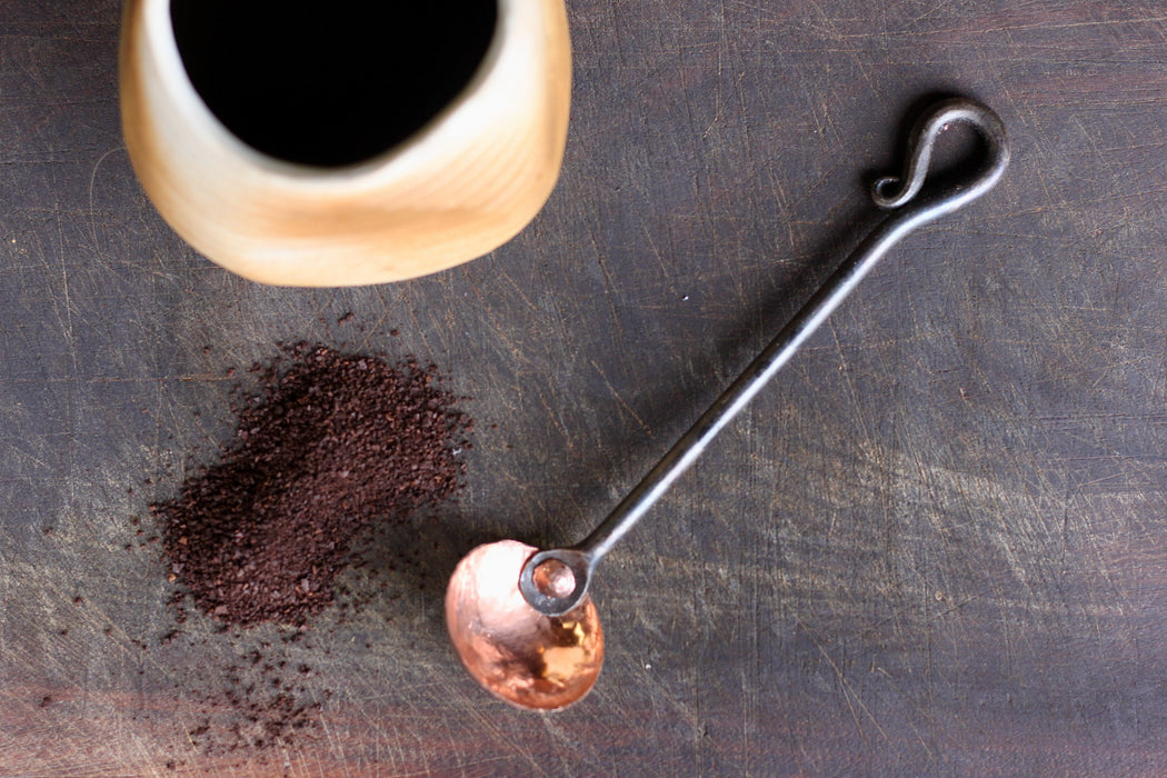 a blacksmith hand forged copper and steel coffee scoop with a reverse curl handle by Wicks Forge