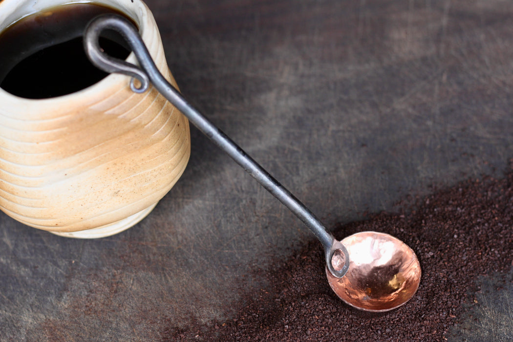 a blacksmith hand forged copper and steel coffee scoop with a reverse curl handle by Wicks Forge