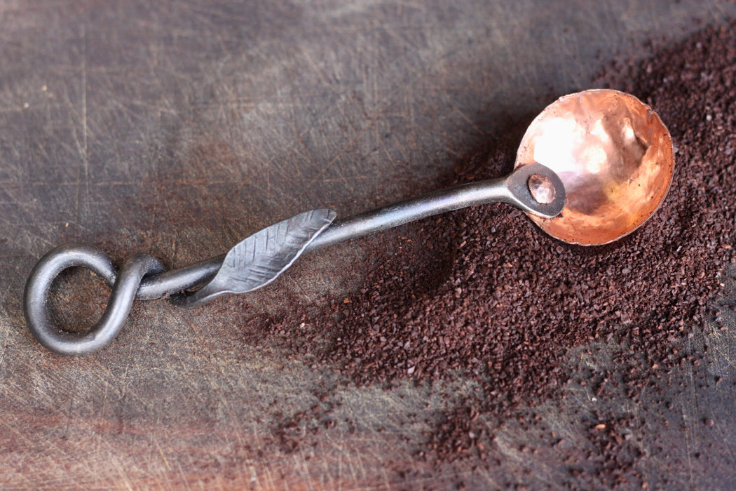 a blacksmith hand forged copper and steel coffee scoop with a leaf handle by Wicks Forge