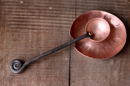 a blacksmith hand forged copper spoon rest under a coffee scoop by Wicks Forge