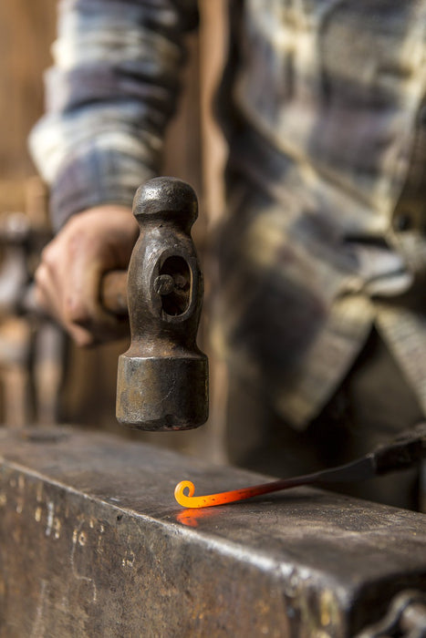 a blacksmith forging a curl out of heated steel