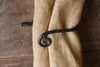 a blacksmith hand forged curtain holdback with a curl design by Wicks Forge