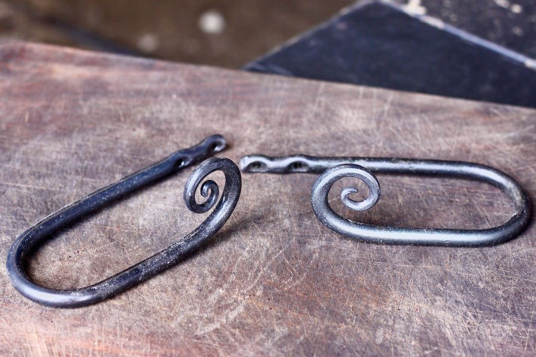 a set of blacksmith hand forged curtain holdback with a curl design by Wicks Forge