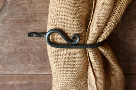 a blacksmith hand forged curtain holdback with a reverse curl design by Wicks Forge