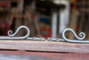 a set of blacksmith hand forged curtain holdback with a reverse curl design by Wicks Forge
