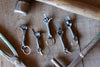5 keychains hand gestures by wicks forge on a wooden surface 