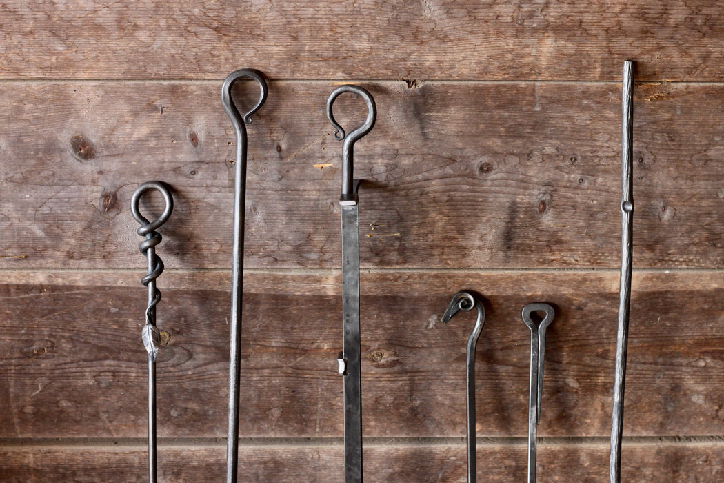 a collection of fire pokers and fireplace tongs by Wicks Forge