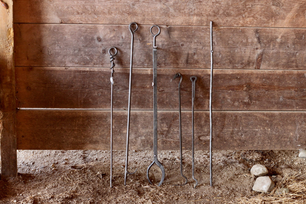 a collection of fire pokers and fireplace tongs by Wicks Forge
