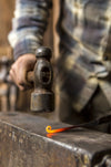a blacksmith forging a curl out of heated by Wicks Forge steel