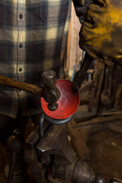 a blacksmith forging an egg spoon dish out of heated steel by Wicks Forge