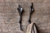 iron Lilly wall hook with a coat hanging on it on a wooden wall 