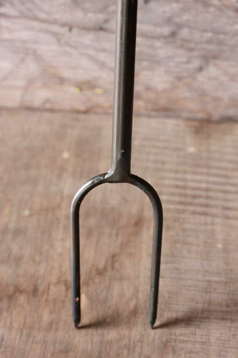 prong of a campfire roaster on a wooden surface 