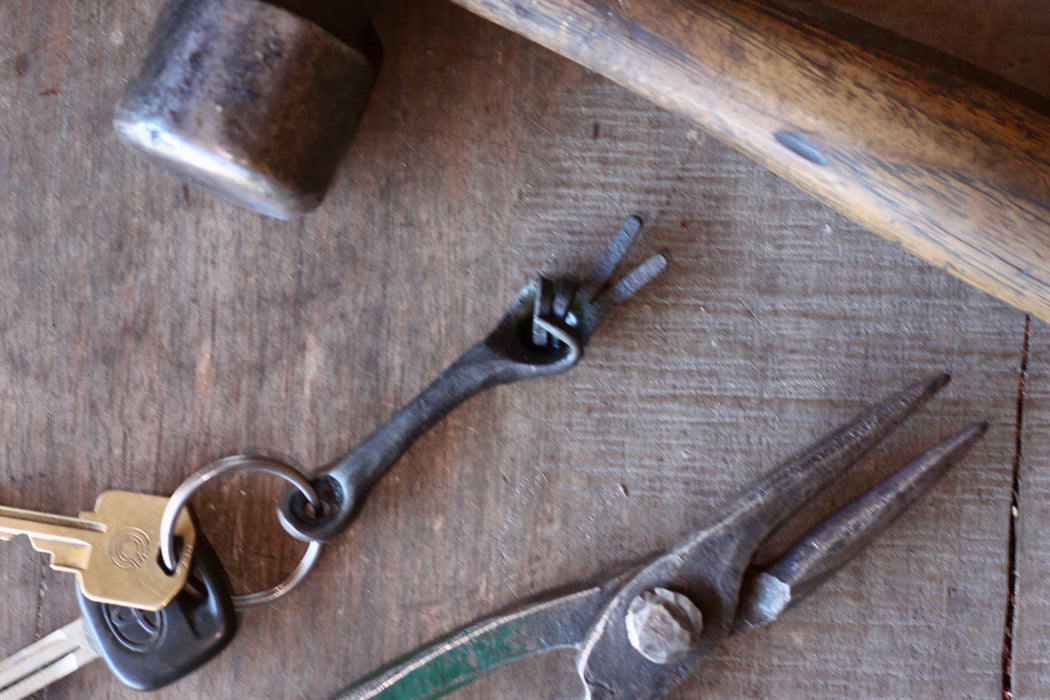 hand keychain and keys with pliers showing on a wooden table 
