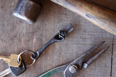 hand keychain and keys with pliers showing on a wooden table 