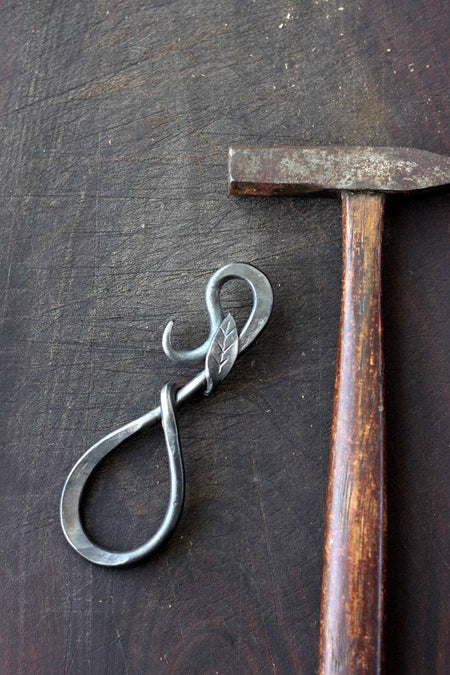 a blacksmith hand forged bottle opener with a leaf design by Wicks Forge