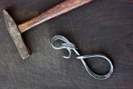 a blacksmith hand forged bottle opener with a leaf design by Wicks Forge