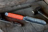 Knife with orange handle on a wooden surface