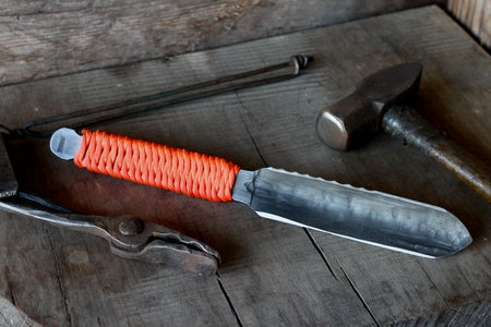 Knife with orange handle on a wooden surface